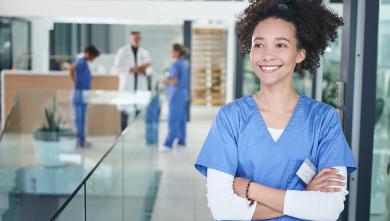 Female dental professional smiling with arms crossed and looking off into the distance.
